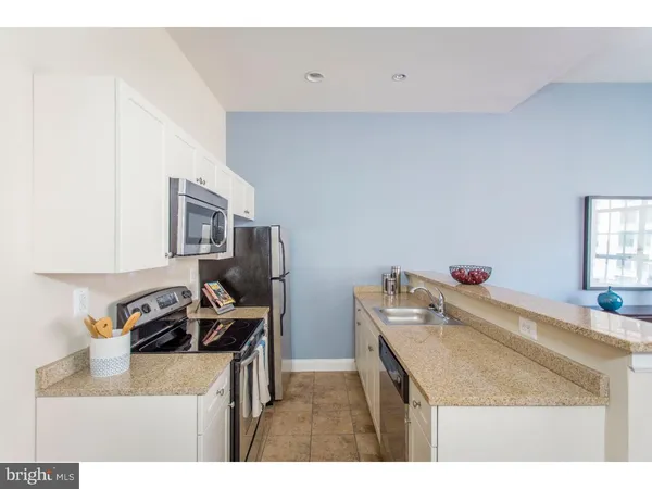 a kitchen with a sink a stove and white cabinets