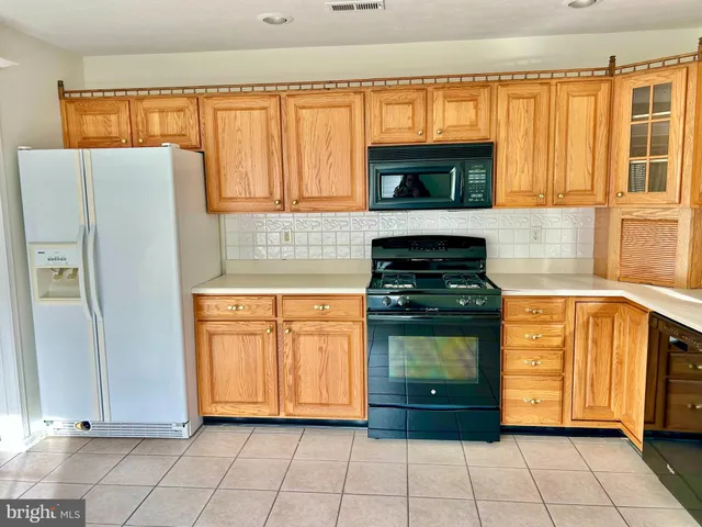 a large kitchen with a stove a refrigerator a sink dishwasher and wooden cabinets