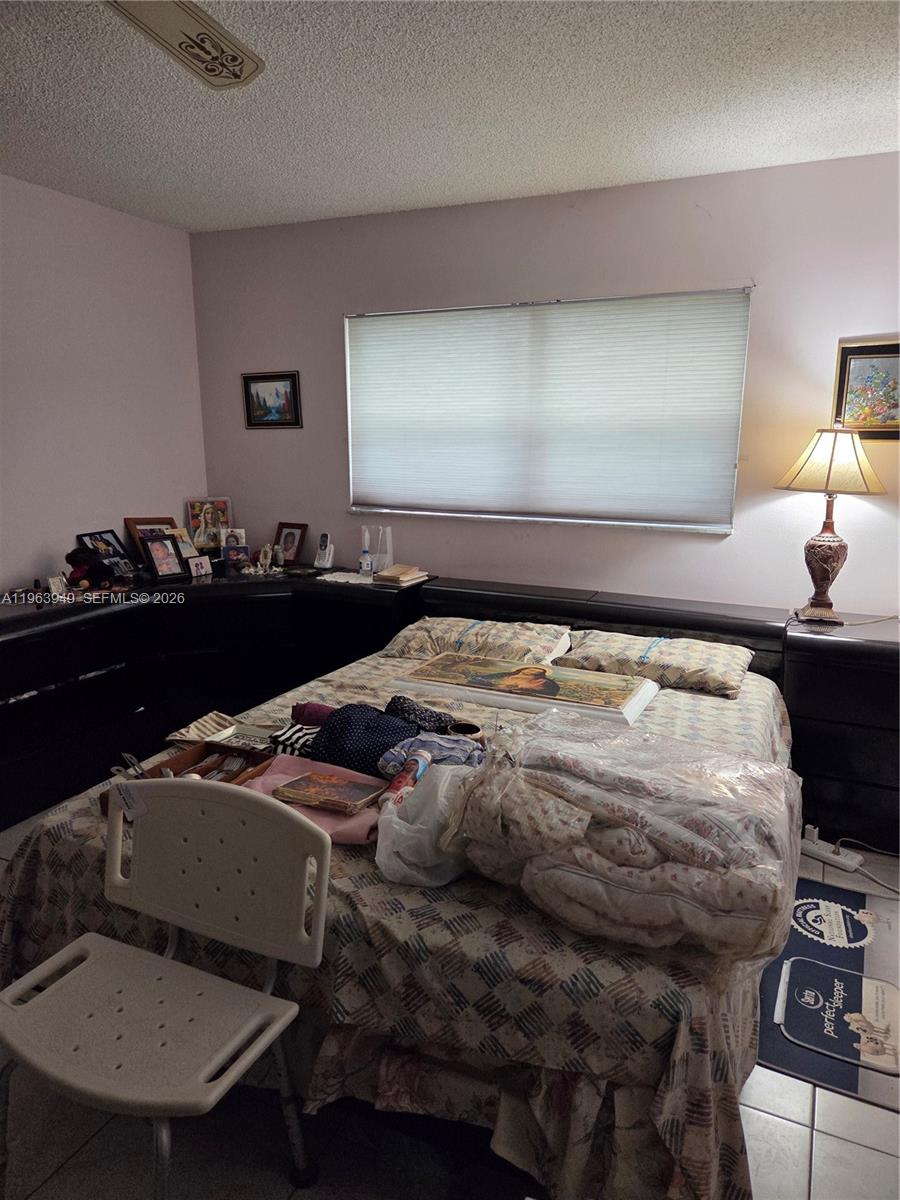 8834 West McNab Road, Unit 201 Tamarac, FL 33321 - Photo 4 of 27 a bed sitting in a bedroom next to a lamp