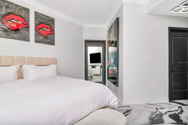 a bedroom with a bed and a flat tv screen on dresser