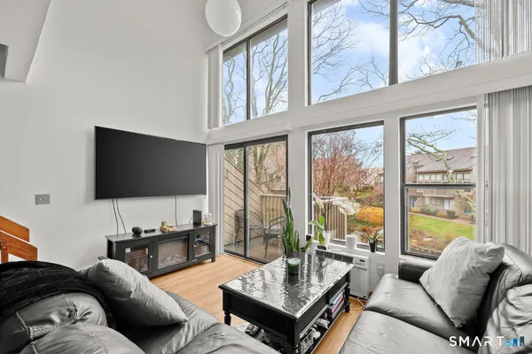 a living room with furniture a flat screen tv and a large window
