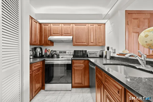 a kitchen with granite countertop a sink stove and cabinets