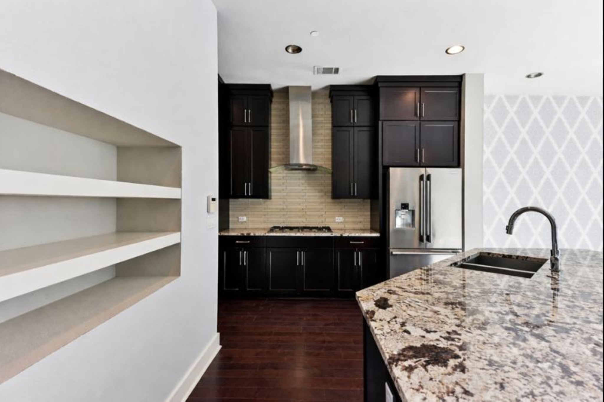 8110 Ranch Road 2222, Unit 98 Austin, TX 78730 - Photo 10 of 37 Kitchen featuring backsplash, light stone countertops, stainless steel appliances, dark cabinets, and wall chimney range hood