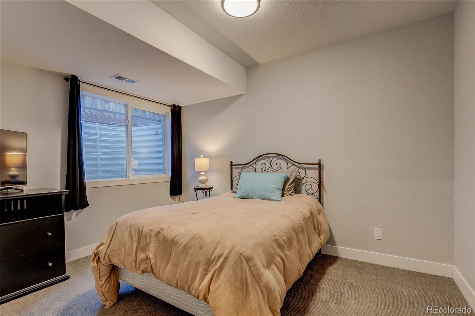 4792 South Acoma Street Englewood, CO 80110 - Photo 16 of 19 a bedroom with a bed and a flat tv screen on dresser