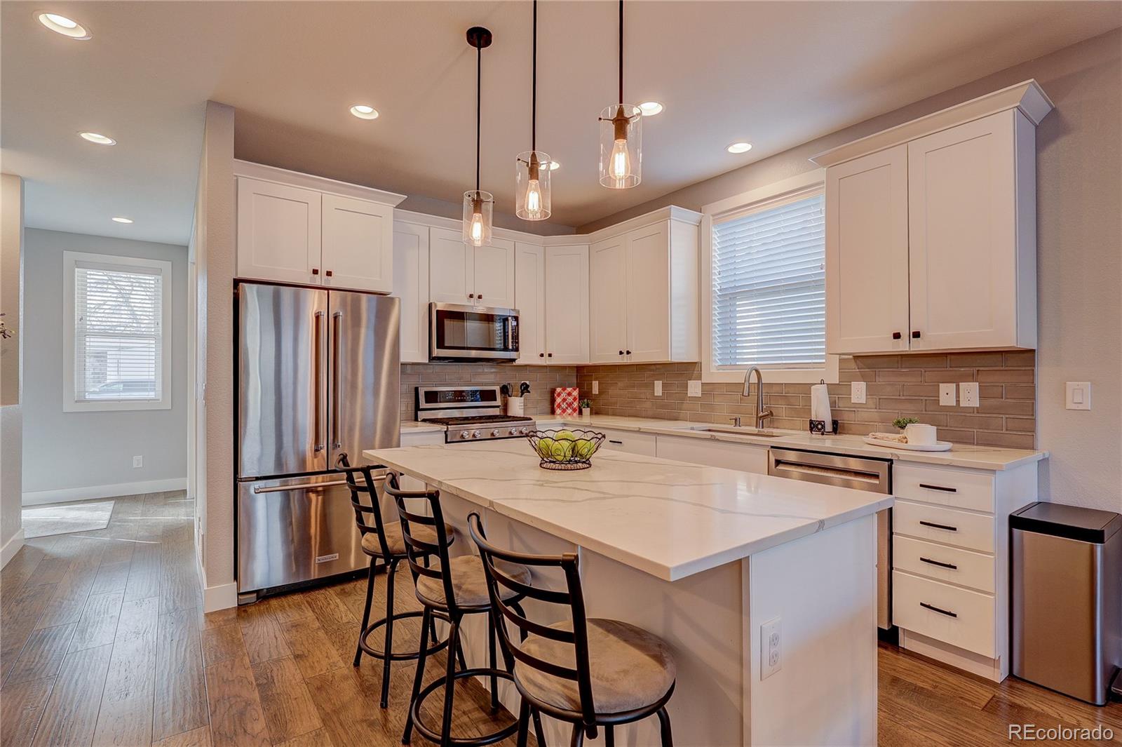 4792 South Acoma Street Englewood, CO 80110 - Photo 2 of 19 a kitchen with stainless steel appliances granite countertop a refrigerator a sink dishwasher a stove a dining table and chairs with wooden floor