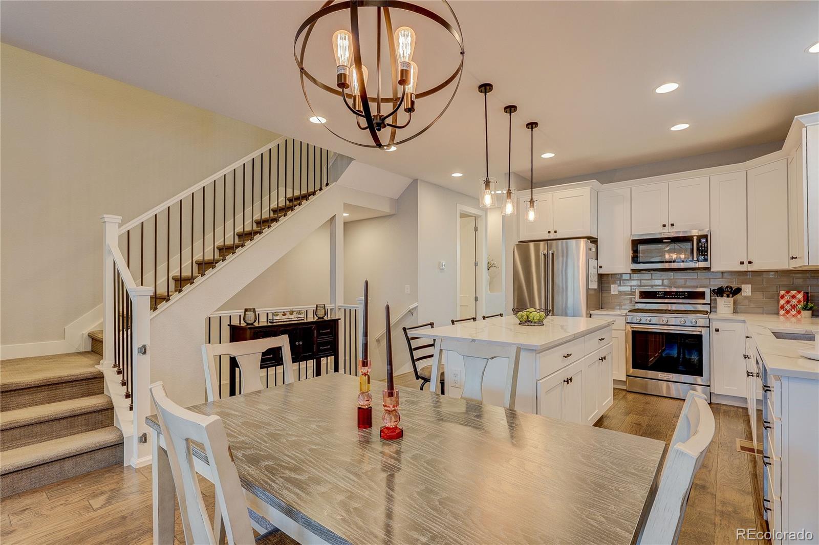 4792 South Acoma Street Englewood, CO 80110 - Photo 5 of 19 a kitchen with stainless steel appliances kitchen island granite countertop a stove a refrigerator a dining table and chairs with wooden floor