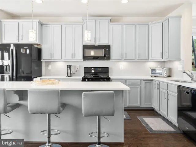 a kitchen with stainless steel appliances a stove a sink a microwave a refrigerator and cabinets