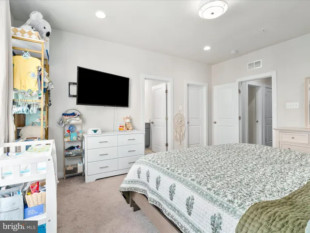 a bedroom with a bed and a flat tv screen on dresser
