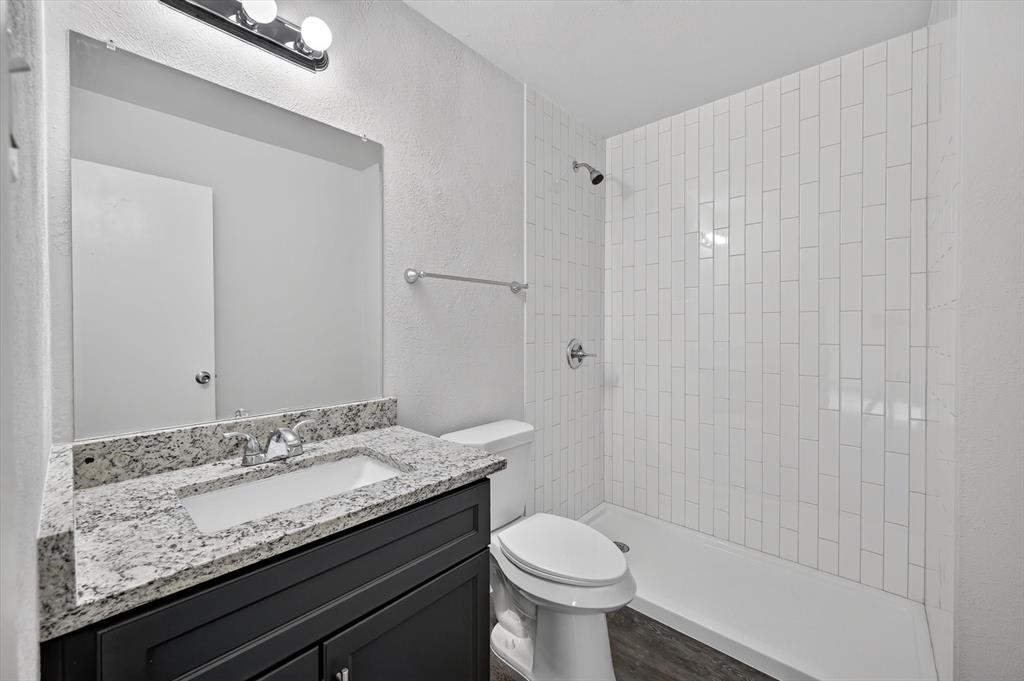 1801 East Grauwyler Road, Unit 101 Irving, TX 75061 - Photo 27 of 39 a bathroom with a granite countertop sink a toilet and shower