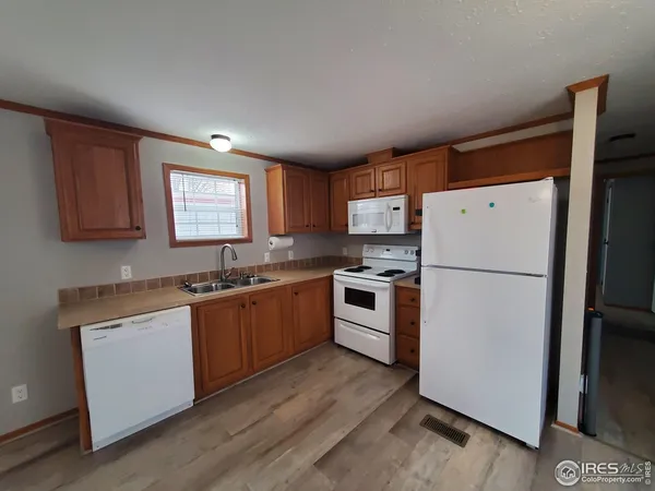 a kitchen with granite countertop appliances a sink a refrigerator a window and cabinets