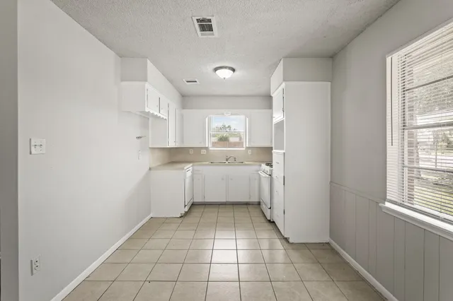 a large white kitchen with a sink a refrigerator and window