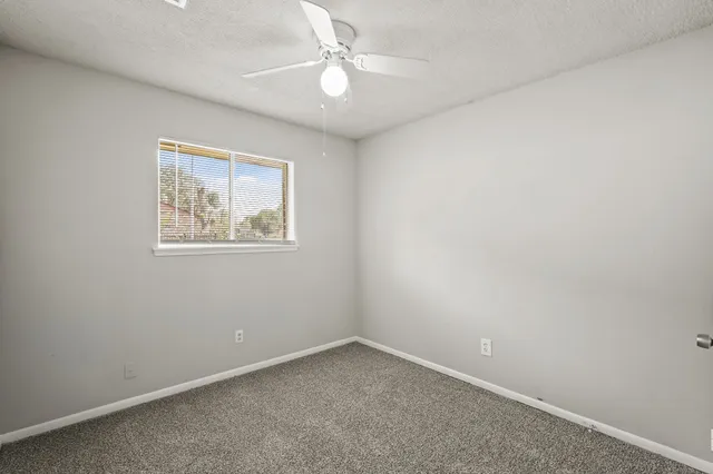 an empty room with a window and a fan