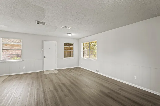 an empty room with wooden floor and windows