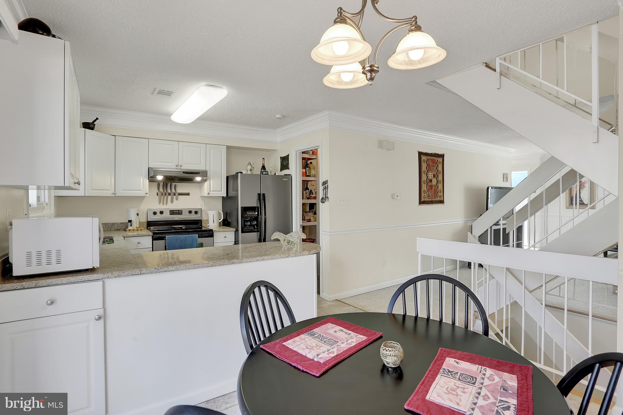 2413 Southgate Square Reston, VA 20191 - Photo 4 of 26 a kitchen with stainless steel appliances kitchen island granite countertop a refrigerator a stove a sink dishwasher and white cabinets with wooden floor