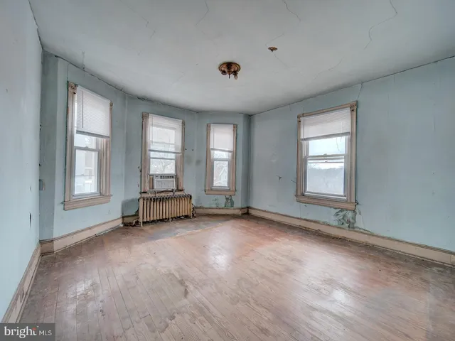 an empty room with windows and ceiling fan