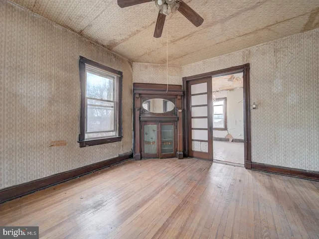 a view of an empty room with a window and wooden floor
