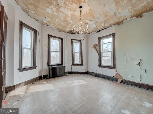 an empty room with chandelier fan and windows