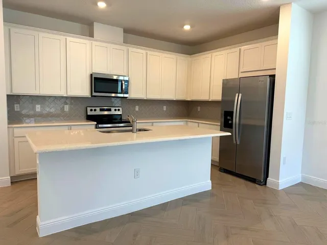 a kitchen with stainless steel appliances a refrigerator a sink a stove a microwave and cabinets