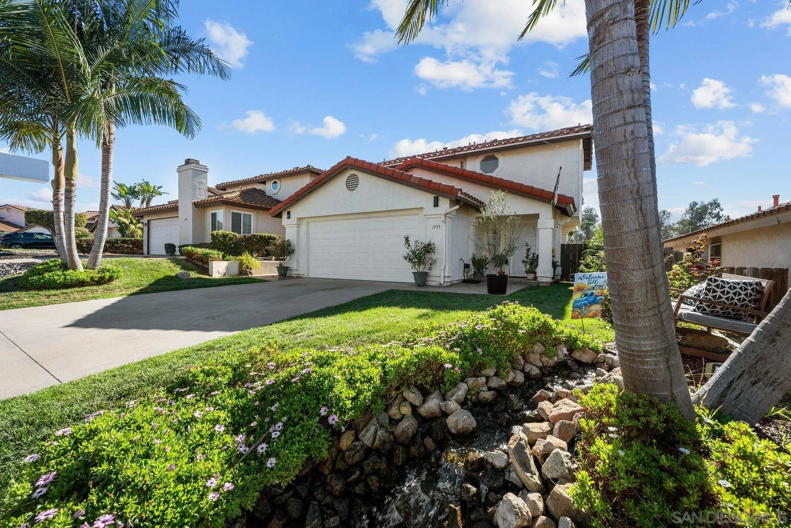 a front view of a house with a yard and potted plants