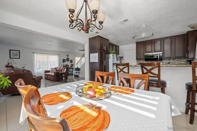 a living room with stainless steel appliances kitchen island granite countertop furniture and a chandelier