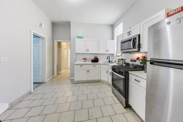 a kitchen with white cabinets a sink stove and refrigerator