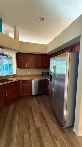 a kitchen with stainless steel appliances granite countertop a refrigerator a sink dishwasher a stove and white countertops with wooden floor