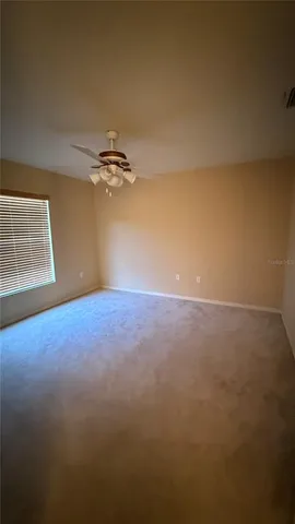 a view of a room with a ceiling fan and carpet