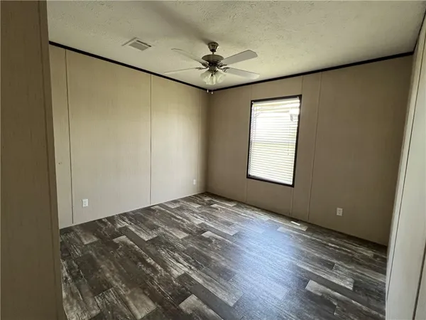 a view of a room with a ceiling fan window and wooden floor