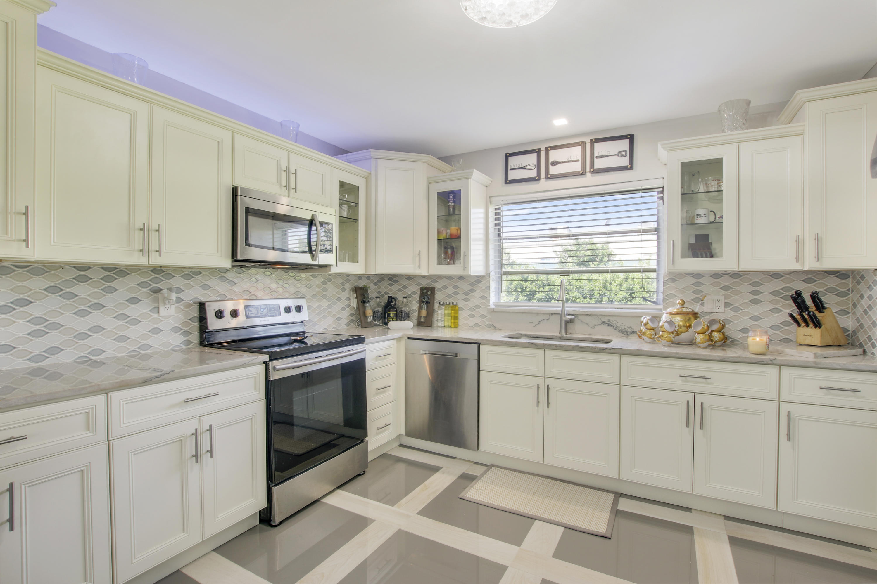 a kitchen with granite countertop white cabinets white stainless steel appliances with a sink and a window