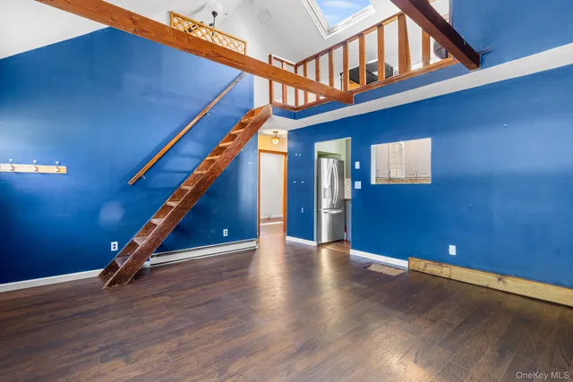 a view of an empty room with wooden floor and windows