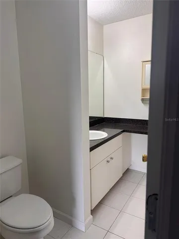 a bathroom with a granite countertop toilet and sink