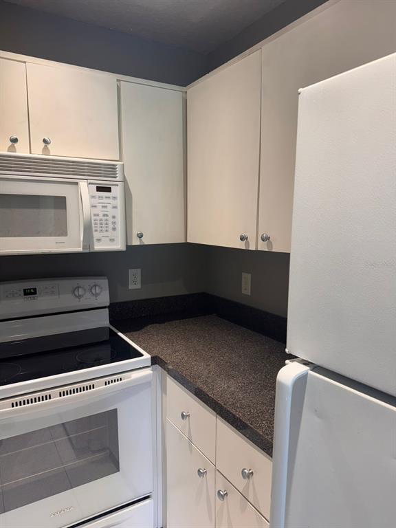 1132 South Pine Ridge Circle, Unit 32 Sanford, FL 32773 - Photo 7 of 26 a kitchen with granite countertop white cabinets and black appliances