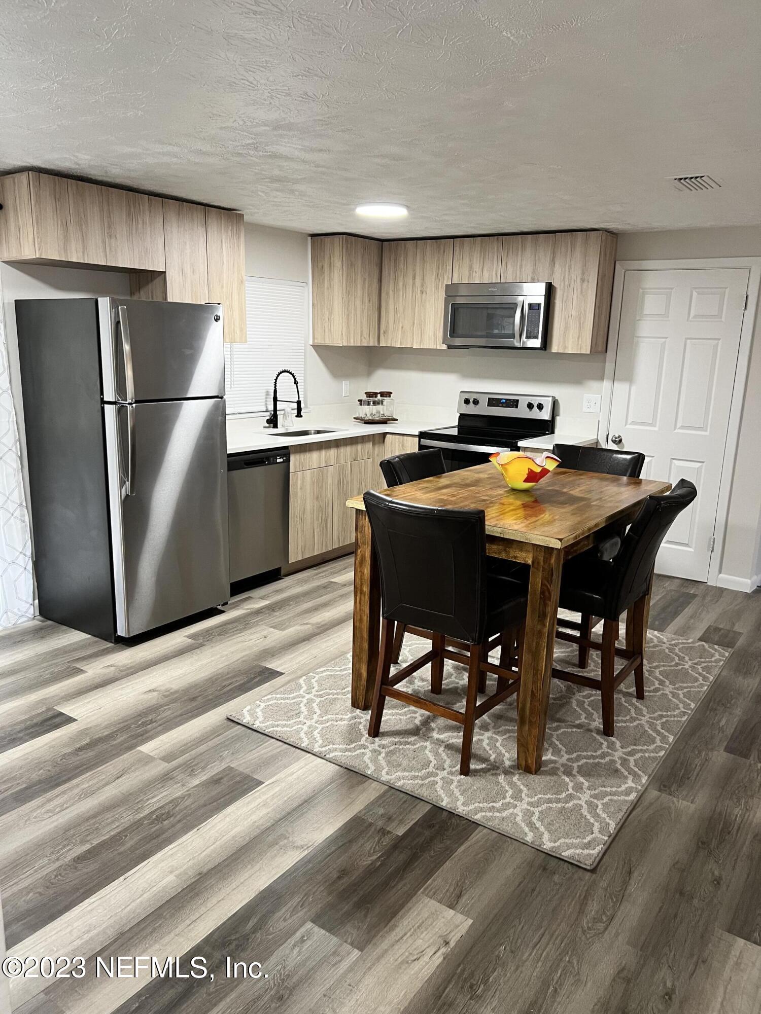 10892 Player Road Jacksonville, FL 32218 - Photo 12 of 37 a kitchen with stainless steel appliances granite countertop a refrigerator a sink a stove a dining table and chairs