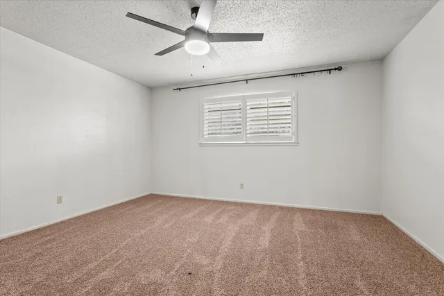 an empty room with chandelier fan