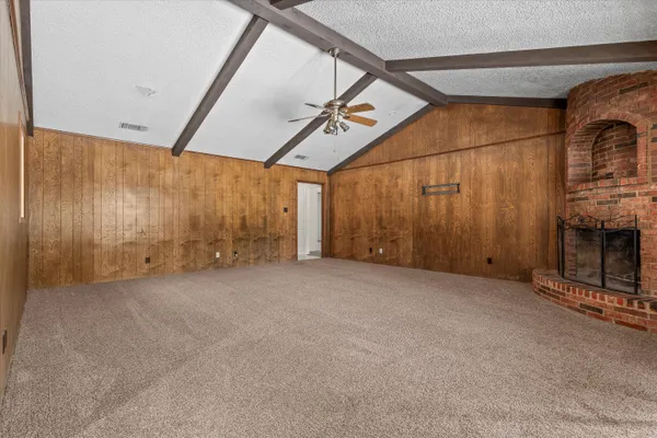 a view of an empty room with window and hardwood floor