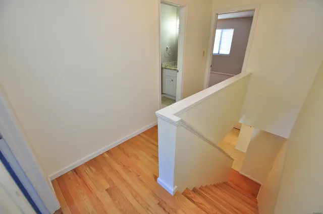 a view of a hallway with wooden floor and staircase