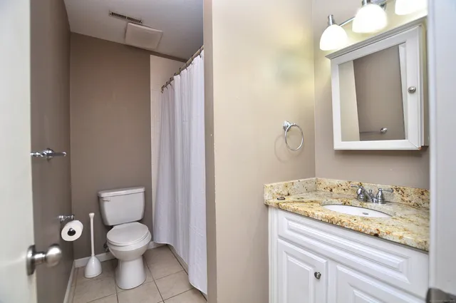 a bathroom with a granite countertop toilet a sink and a mirror