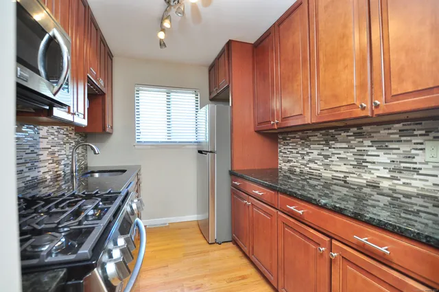 a kitchen with stainless steel appliances granite countertop a stove a sink and a microwave