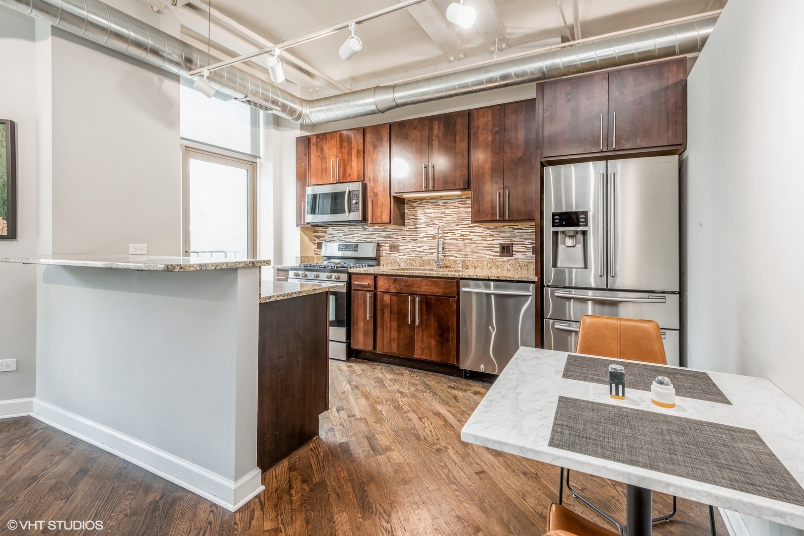 500 South Clinton Street, Unit 403 Chicago, IL 60607 - Photo 4 of 13 a kitchen with stainless steel appliances granite countertop a refrigerator a sink dishwasher a stove with wooden cabinets and floor