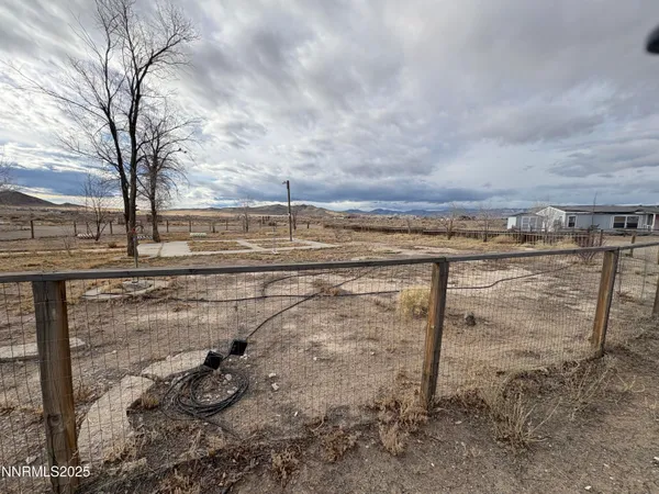 a view of a dry yard with wooden fence