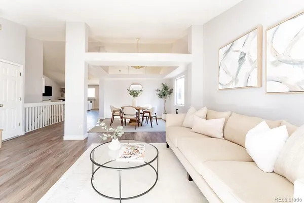 a living room with furniture and a dining table with wooden floor