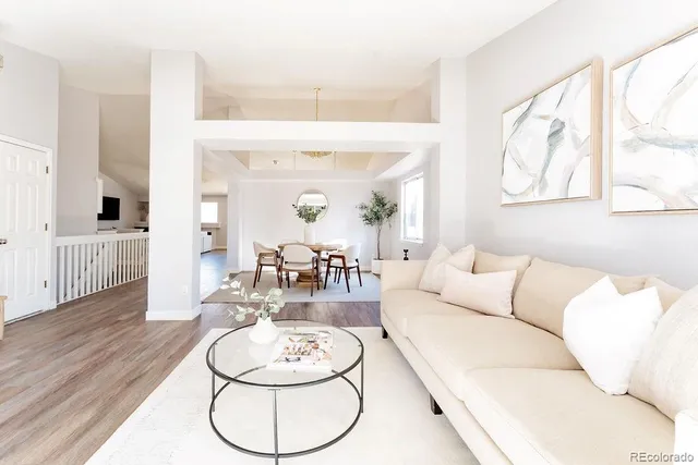 a living room with furniture and a dining table with wooden floor