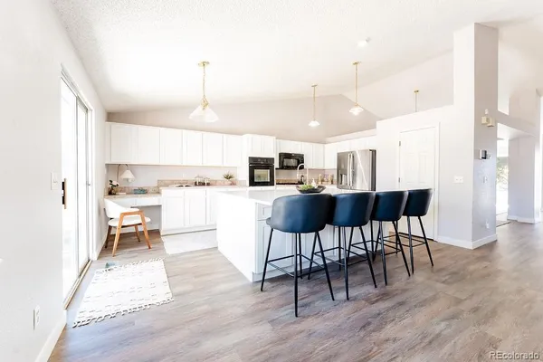 a open kitchen with stainless steel appliances granite countertop a stove refrigerator and a dining table with wooden floor