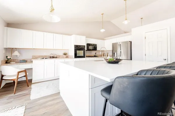 a kitchen with kitchen island a stove a sink a oven a counter top space and cabinets