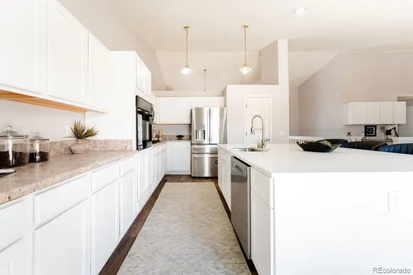 a large kitchen with a large counter top a sink a counter space and stainless steel appliances