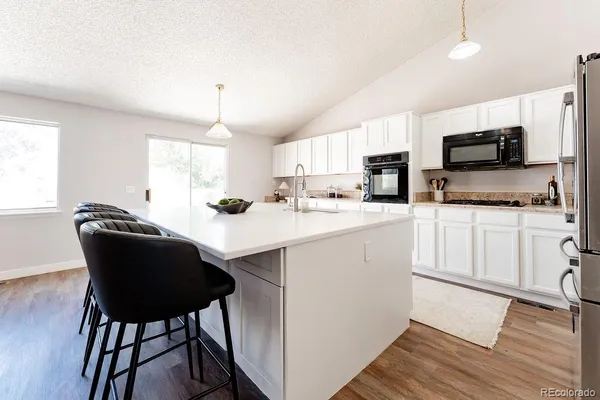 a kitchen with a dining table chairs microwave and refrigerator