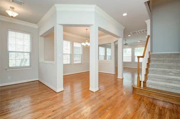 a view of a room with wooden floor chandelier and windows