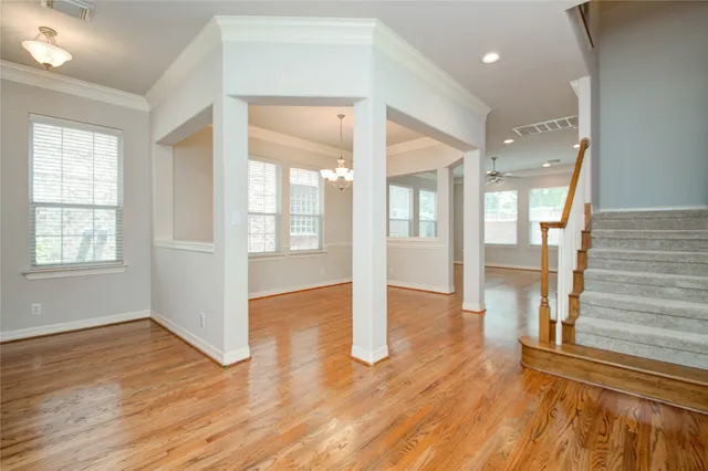 a view of a room with wooden floor chandelier and windows