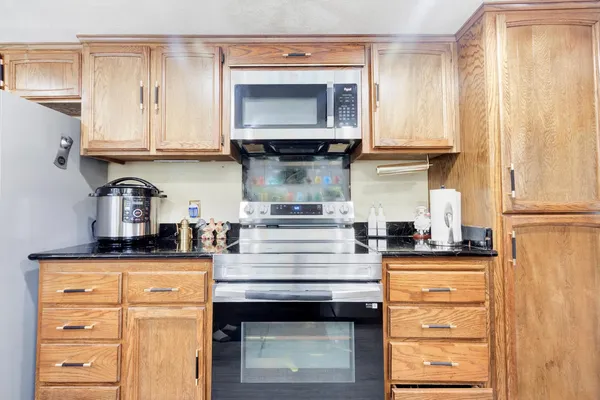 a open dining room with stainless steel appliances kitchen island granite countertop a table chairs and a refrigerator