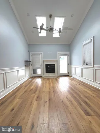 an empty room with wooden floor fireplace and windows